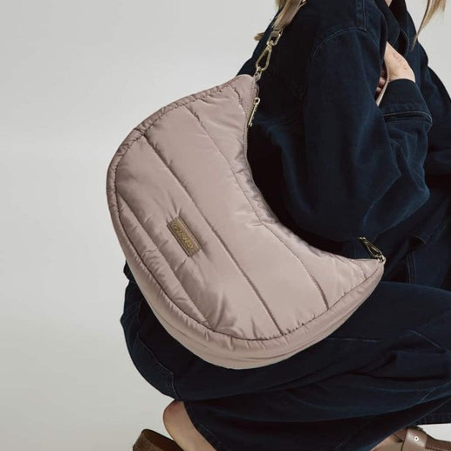 Lieblingstasche Lifetime Buddy M quilted beige hobo bag worn by a woman in dark denim clothing