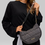Lieblingstasche Lifetime Buddy S quilted charcoal grey crescent crossbody bag worn by a woman