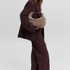 Lieblingstasche Lifetime Sister Suede M taupe suede hobo bag carried by a woman in a dark burgundy suit