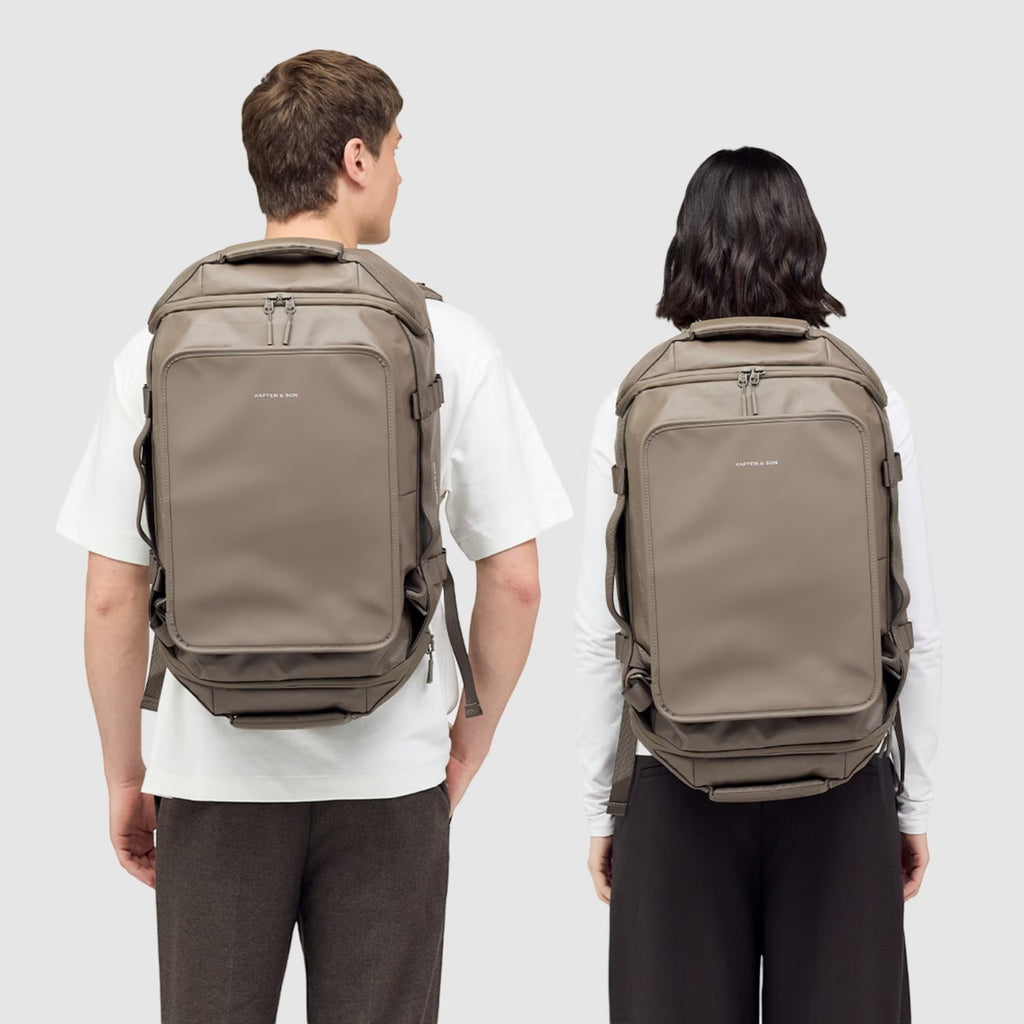 Lieblingstasche Lisbon Duffle Backpack M in taupe worn by a man and a woman against a light grey background