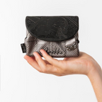 Lieblingstasche metallic grey and black Anekke purse with textured finish and decorative embellishments held in hand