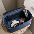 Lieblingstasche navy blue beautycase with organized makeup brushes and accessories inside on a wicker stool