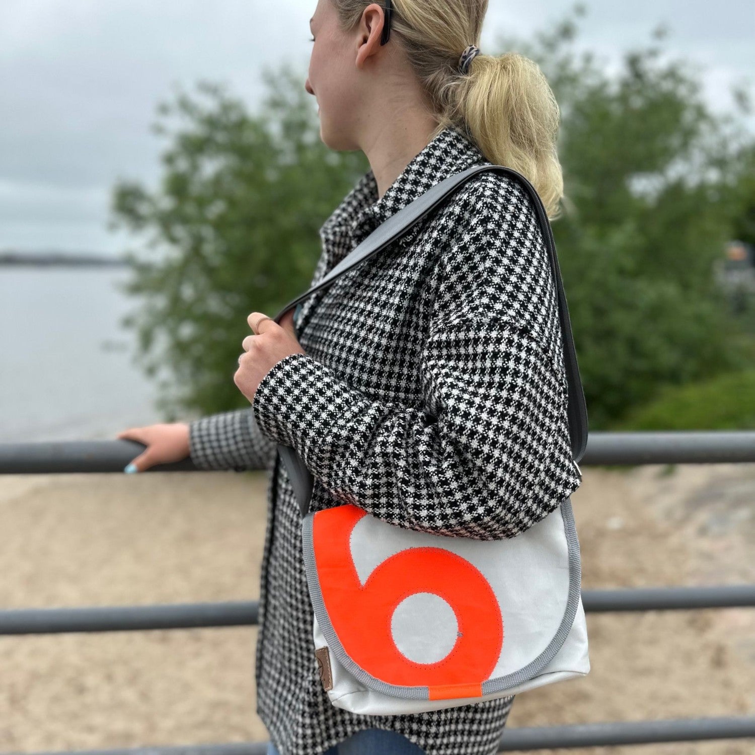 Lieblingstasche Perle white messenger bag with a bold orange circular logo worn over the shoulder by a woman