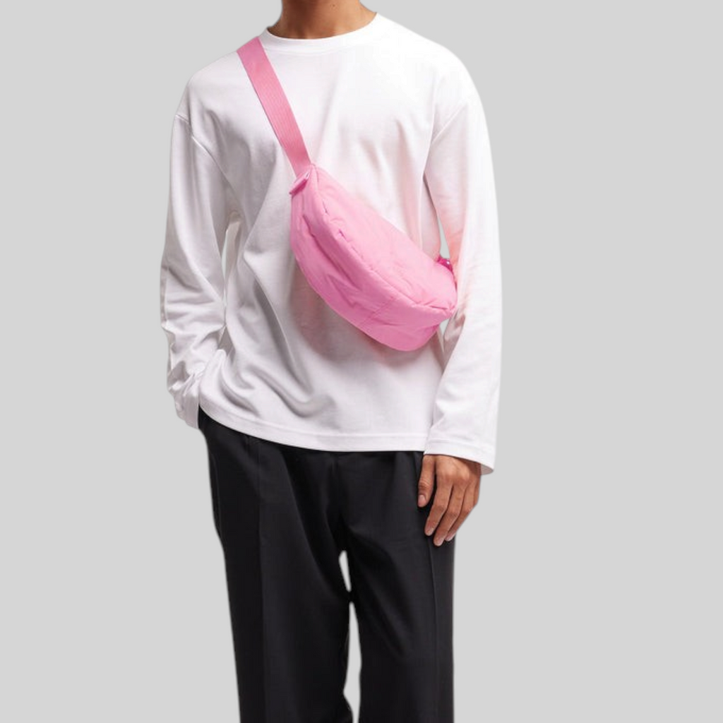 Model wearing a Lieblingstasche Cloud Moon Bag Small in bright pink, styled as a crossbody bag over a white shirt.