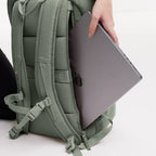 Lieblingstasche Pro Pack sage green backpack with a laptop being inserted into the external 15-inch compartment.