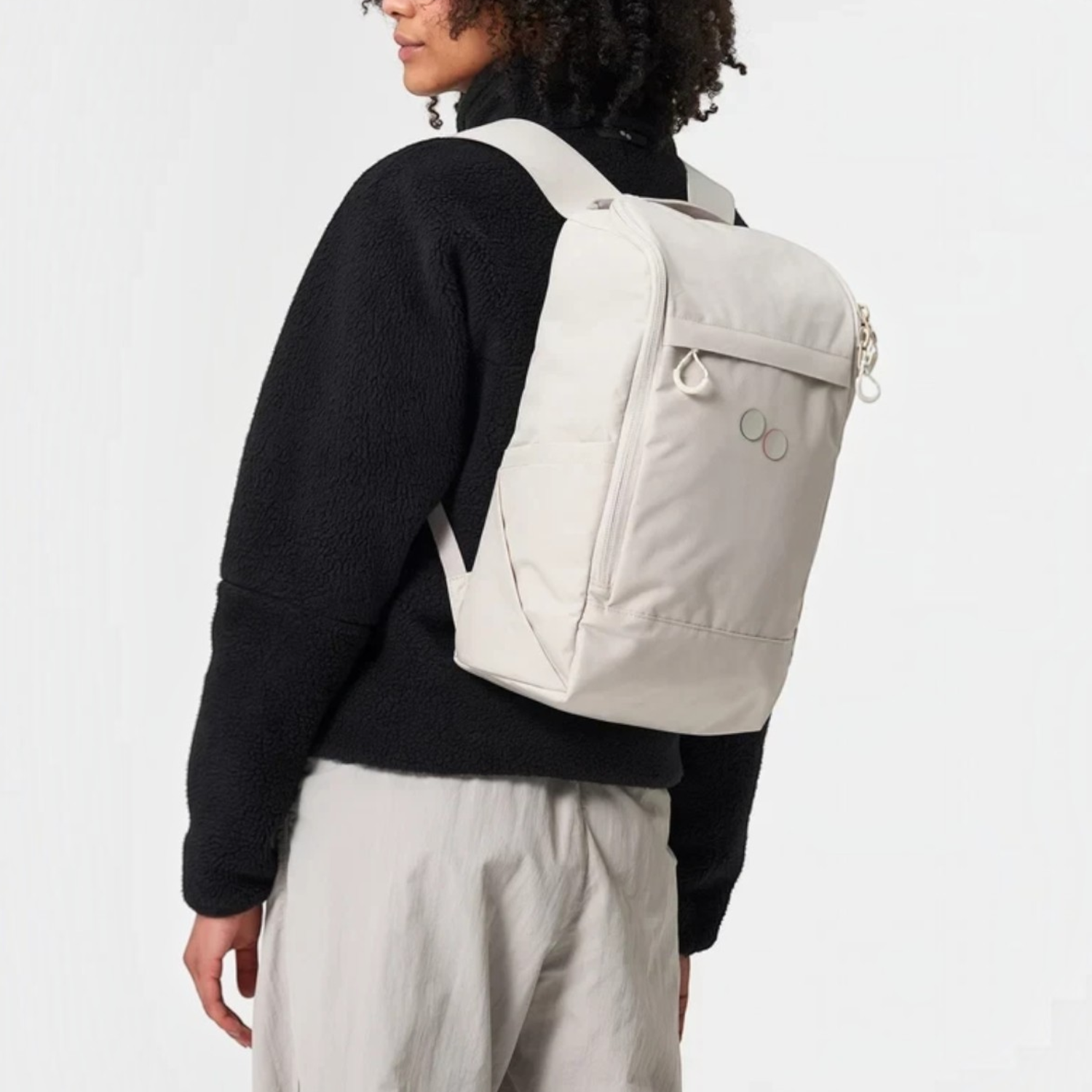 Lieblingstasche Purik backpack in light beige worn by a woman with curly hair against a plain studio background