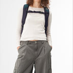 Model wearing a dark blue Lieblingstasche Roll Pack 2.0 backpack with adjustable chest strap on a white background
