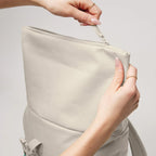 Lieblingstasche Rolltop Easy Small backpack in beige with hands opening the water-resistant zipper closure