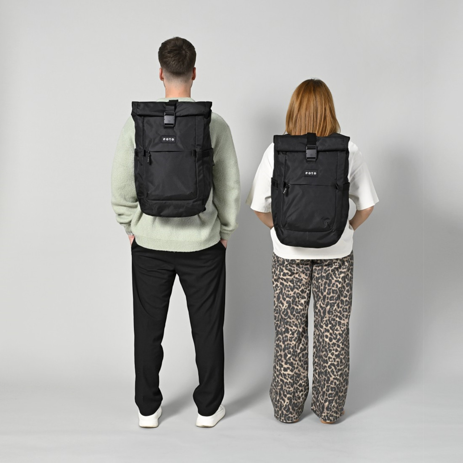 Lieblingstasche Rolly32 black recycled rolltop backpack worn by a man and a woman, back view