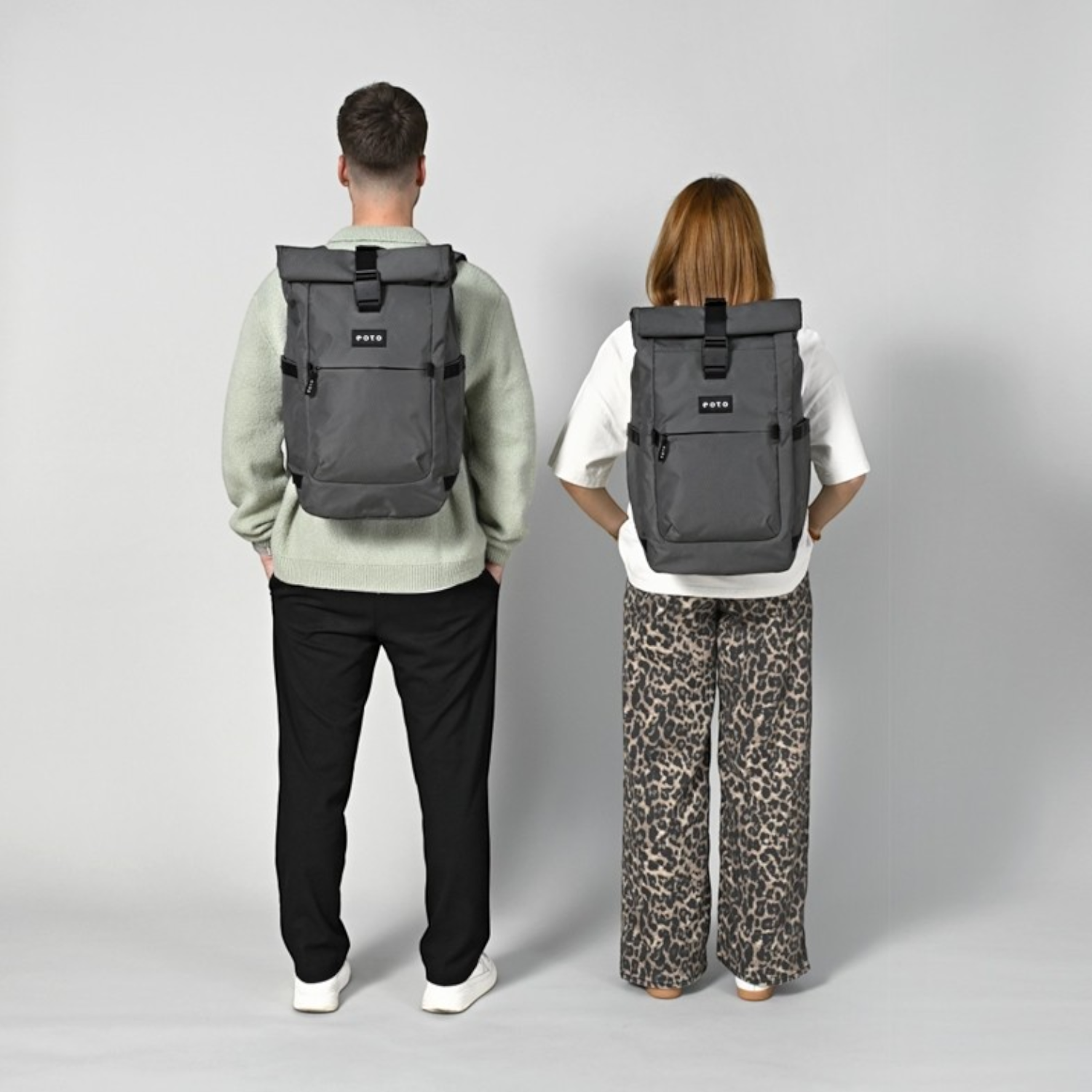 Lieblingstasche Rolly32 grey rolltop backpack worn by a man and woman, showing the back view and adjustable straps.