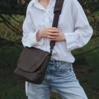 Lieblingstasche Sendai dark brown messenger bag worn crossbody by a woman in a white shirt and blue jeans