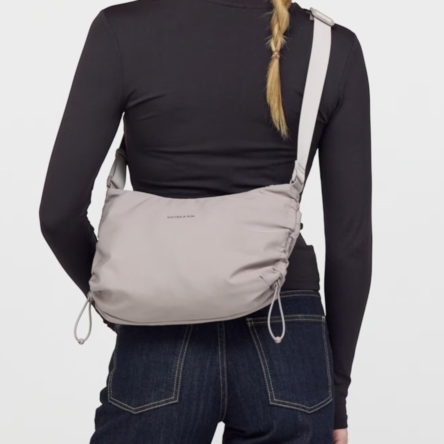 Lieblingstasche Skara Small grey crossbody bag worn by a woman in a black long-sleeve top and dark blue jeans