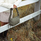 Lieblingstasche Skara Small olive green quilted shoulder bag with a gathered handle held by a person in a field