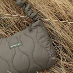 Lieblingstasche Skara Small Quilted bag in olive green with a ruched handle, resting in dry grass.