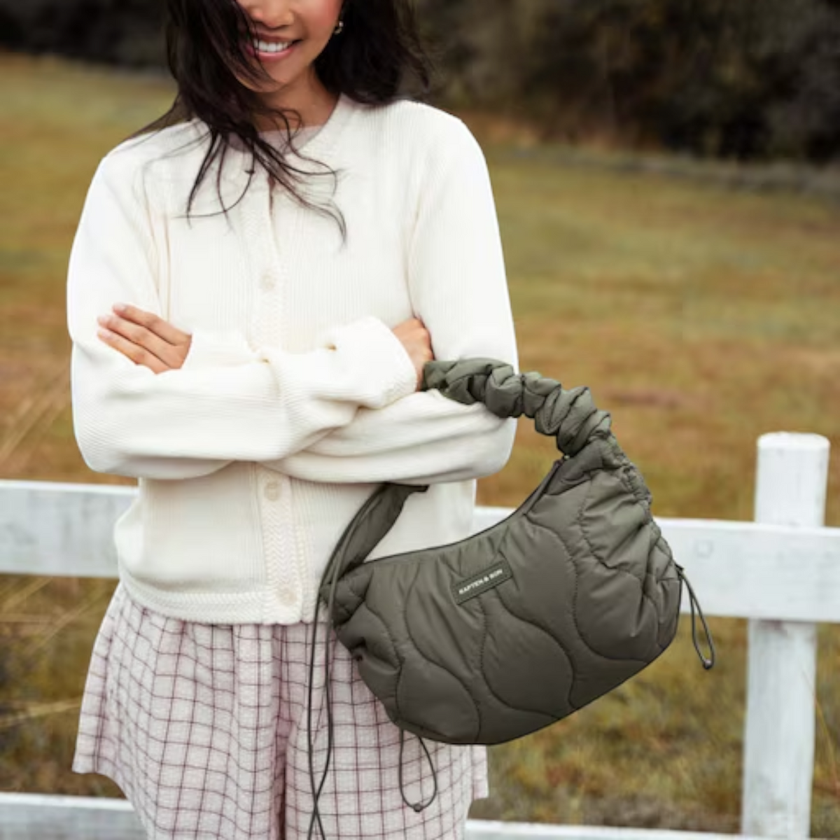 Lieblingstasche Skara Small Quilted olive green shoulder bag with a ruched handle worn by a smiling woman outdoors