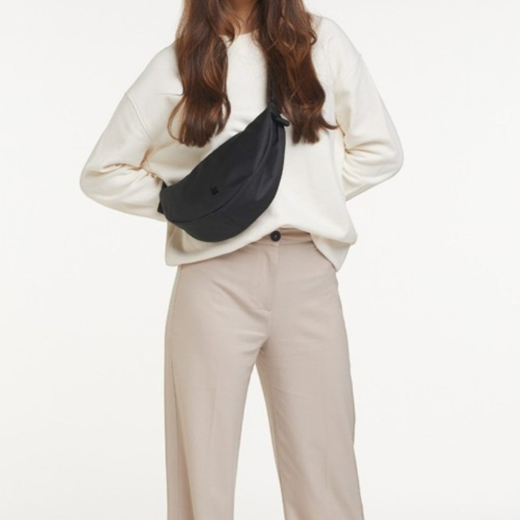 Lieblingstasche small black nylon moon bag worn across the chest by a woman.