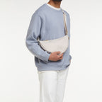 Lieblingstasche small moon bag in light beige canvas worn crossbody by a man.