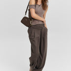 Model wearing a Lieblingstasche Style Mate dark brown crossbody bag with a casual brown top and wide-leg trousers