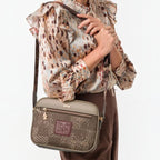 Woman wearing a Lieblingstasche cross-body bag in taupe and metallic bronze with a patterned front panel