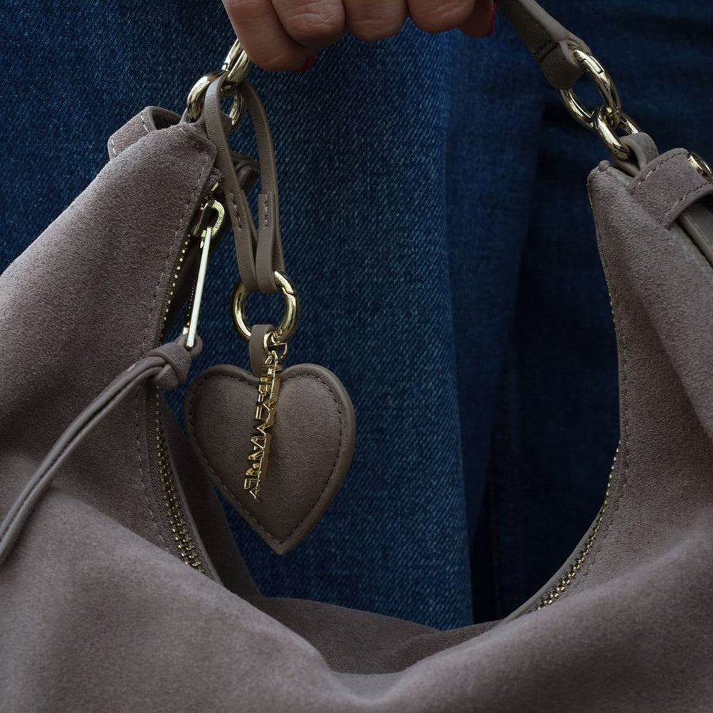 Lieblingstasche heart charm in taupe suede hanging from a matching handbag with gold hardware