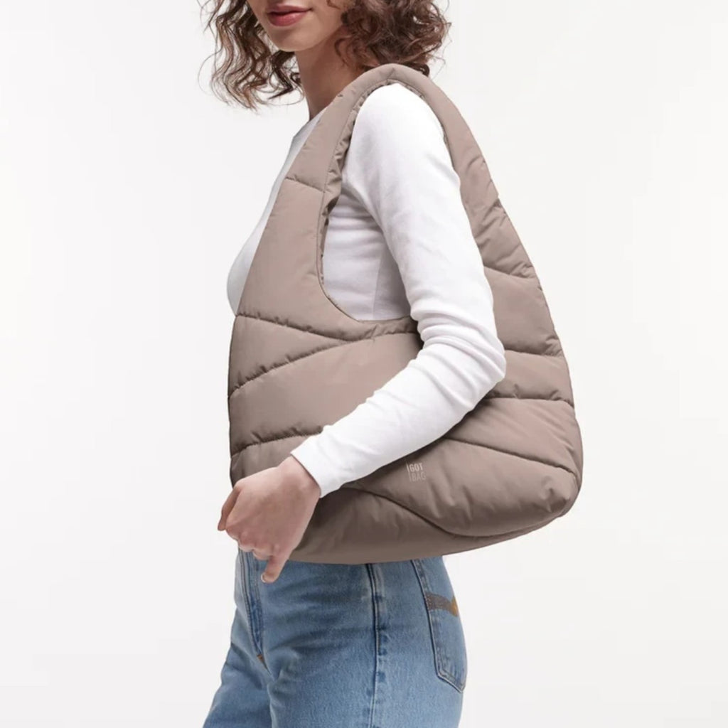 Lieblingstasche wavy puffer shoulder bag in taupe, worn by a woman against a white background.