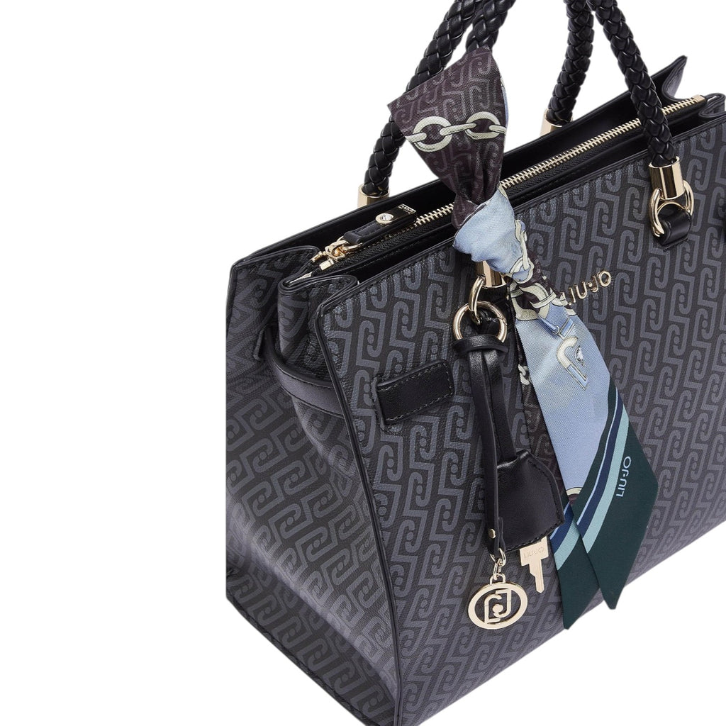 Lieblingstasche Tote M handbag in black with a patterned logo print, braided handles, and a decorative silk scarf.