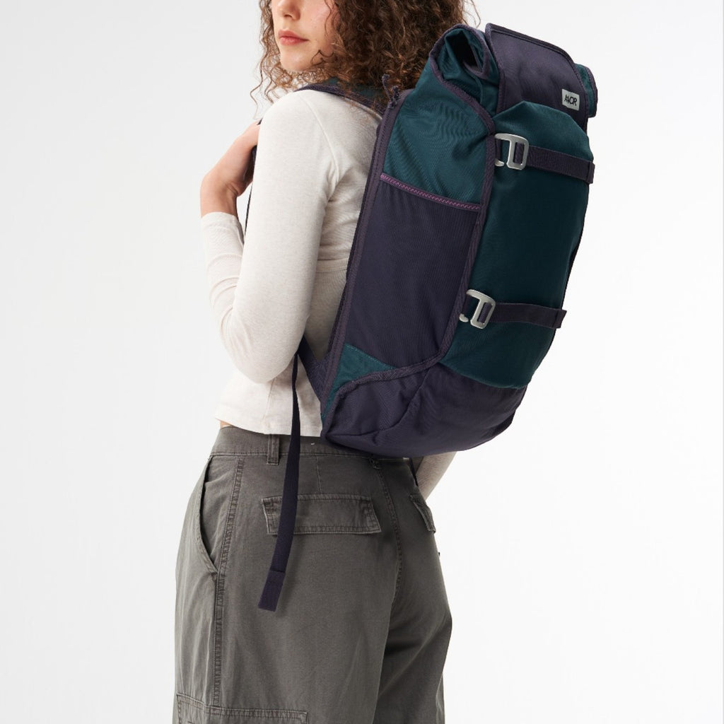 Lieblingstasche Trip Pack backpack in dark green and navy blue worn by a woman against a white background
