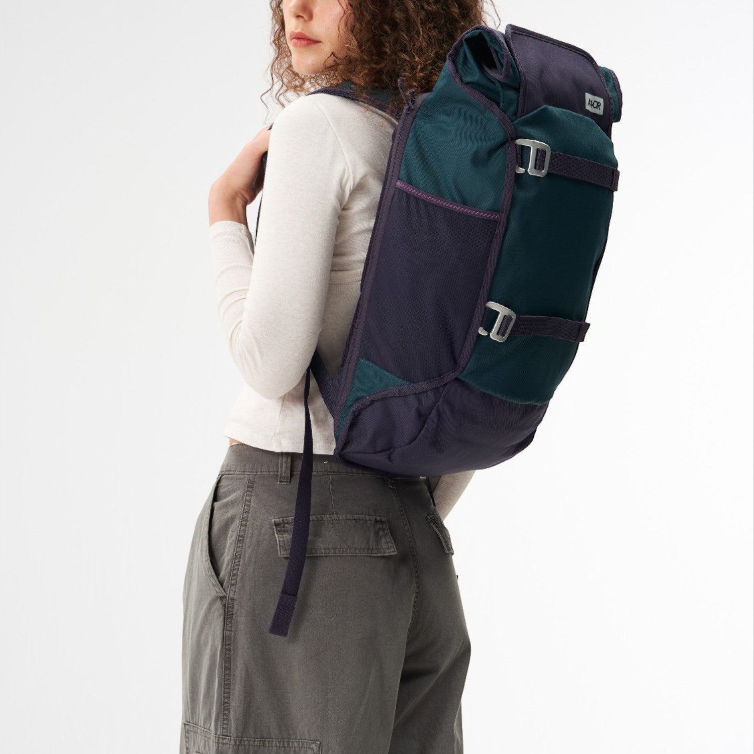 Lieblingstasche Trip Pack backpack in dark green and navy blue worn by a woman against a white background